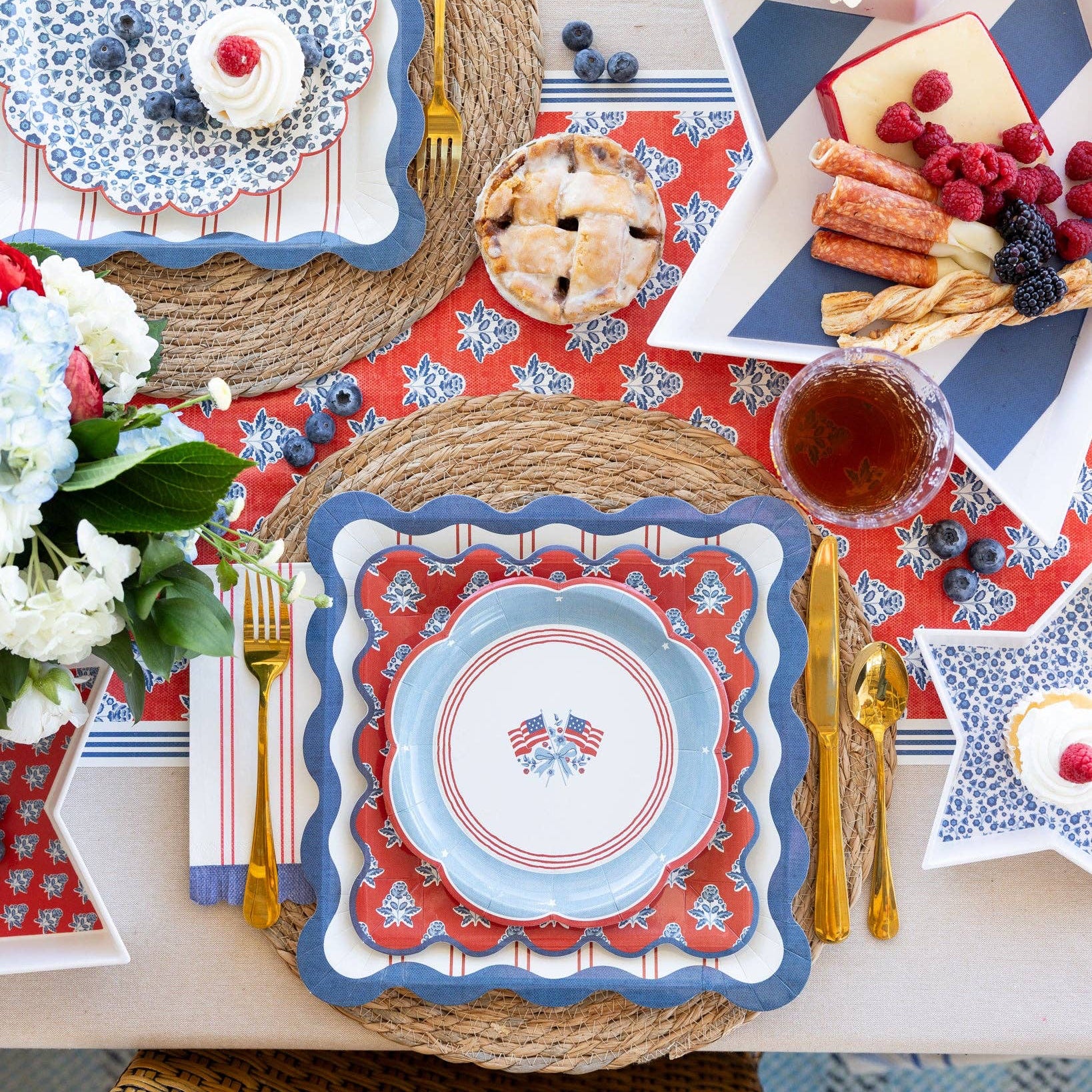 Dining table setting with red, white, and blue theme featuring plates, cutlery, and desserts.