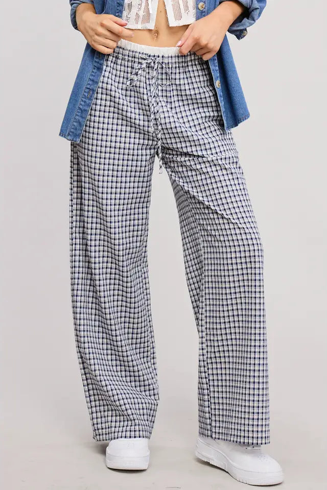 Person wearing checkered pants with a denim jacket on a light gray background