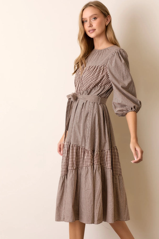 Woman wearing a brown checkered dress against a beige background