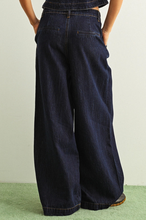Person wearing dark blue wide-leg jeans on a light green background
