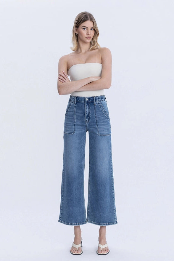 Woman wearing a strapless top and wide-leg jeans on a white background