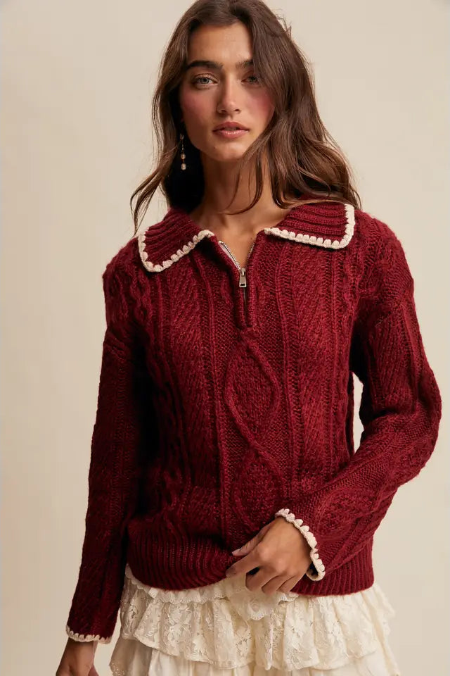 Woman wearing a red knitted sweater with white trim on a beige background