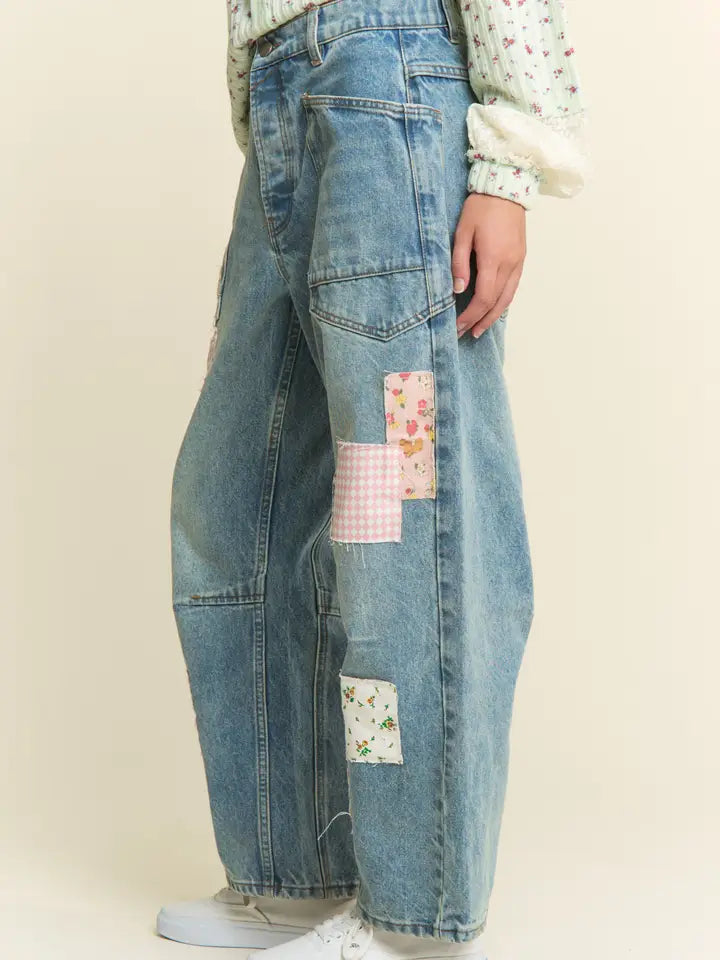 Blue jeans with floral patches on a plain background