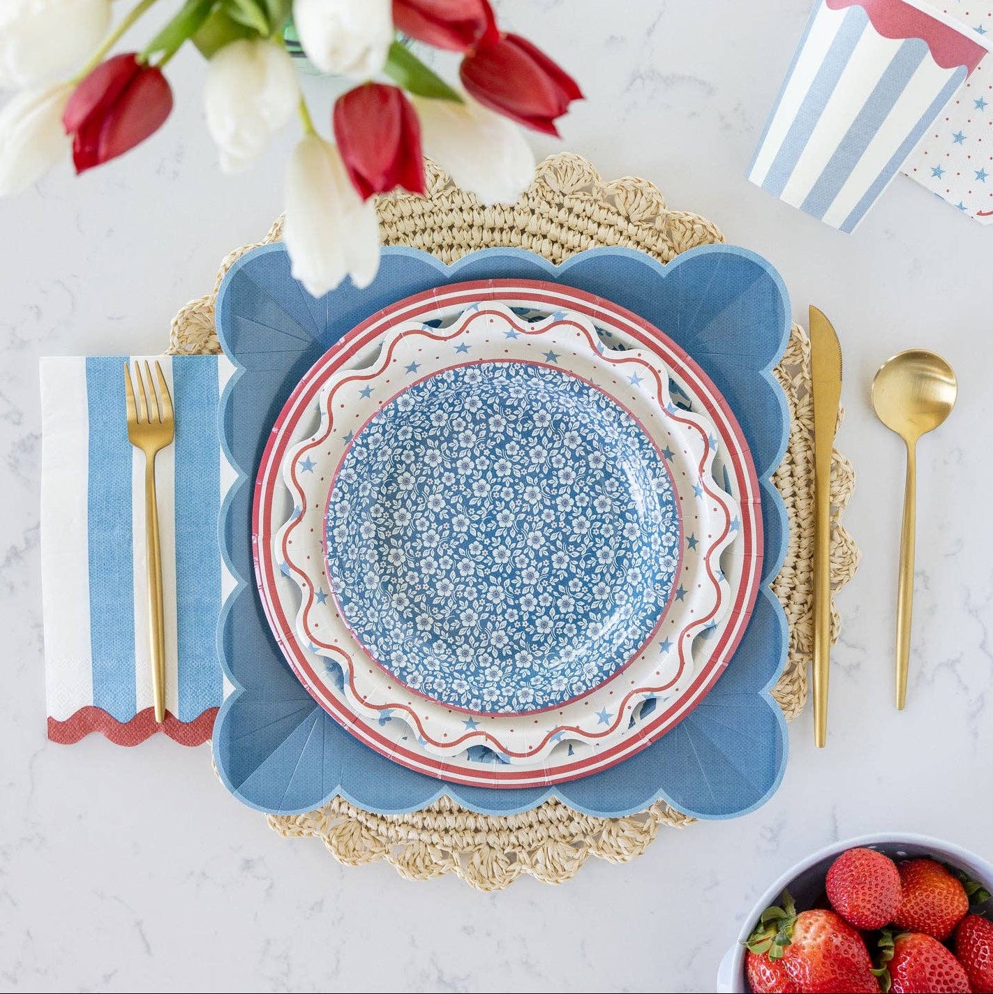 Elegant table setting with floral arrangement, plates, cutlery, and strawberries on a textured surface.