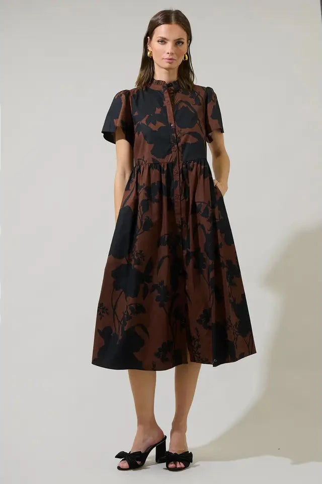 Woman wearing a brown and black floral dress against a white background