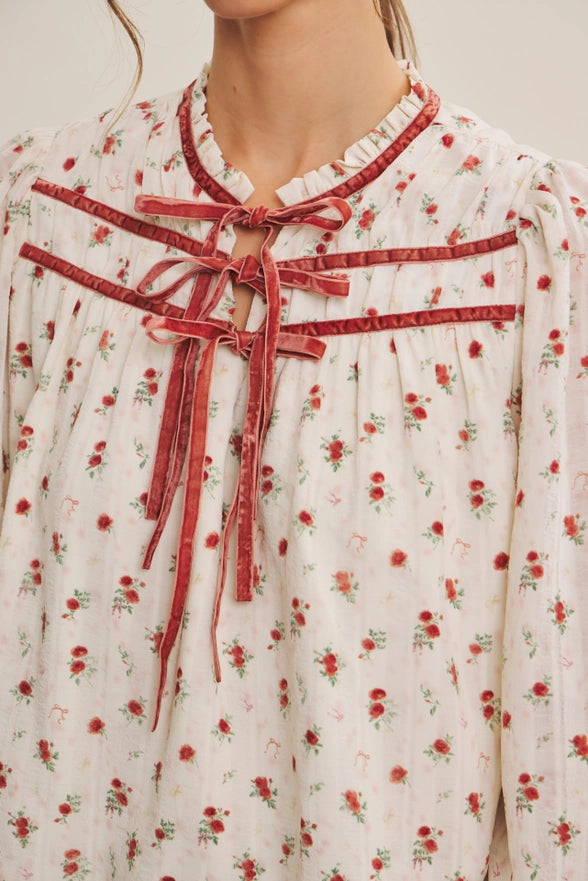 Floral dress with a red ribbon detail on a neutral background