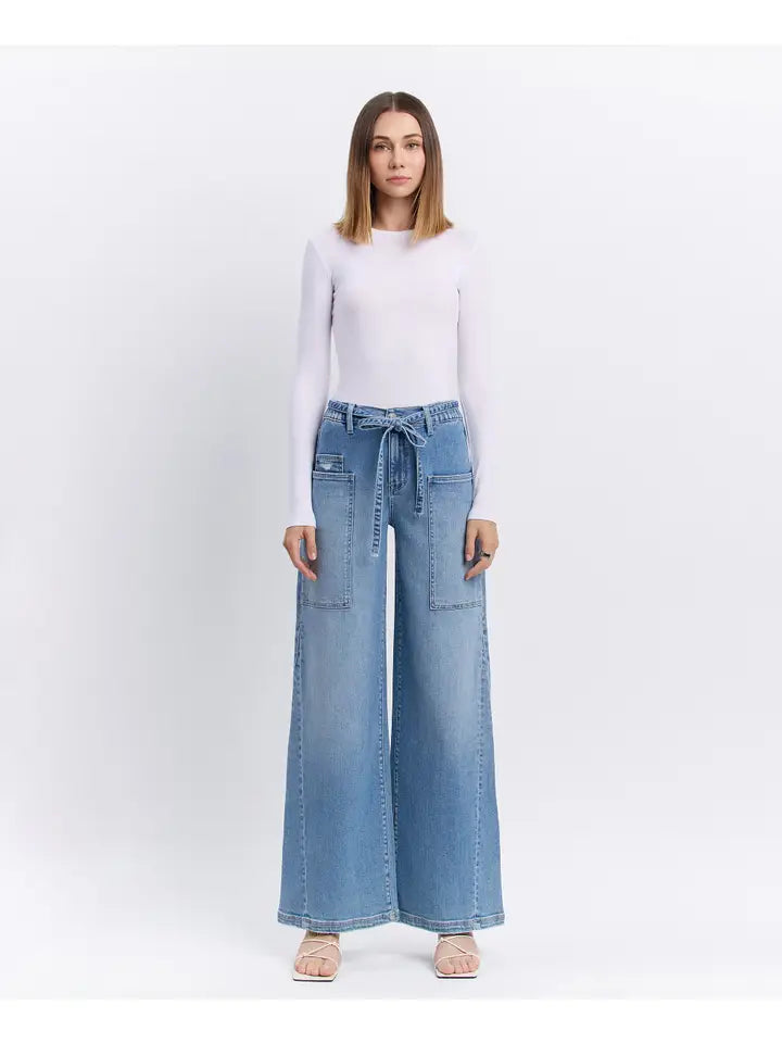 Woman wearing light blue wide-leg jeans on a white background