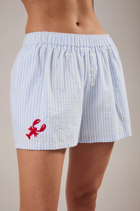 Light blue striped boxer shorts with a red lobster design on a neutral background