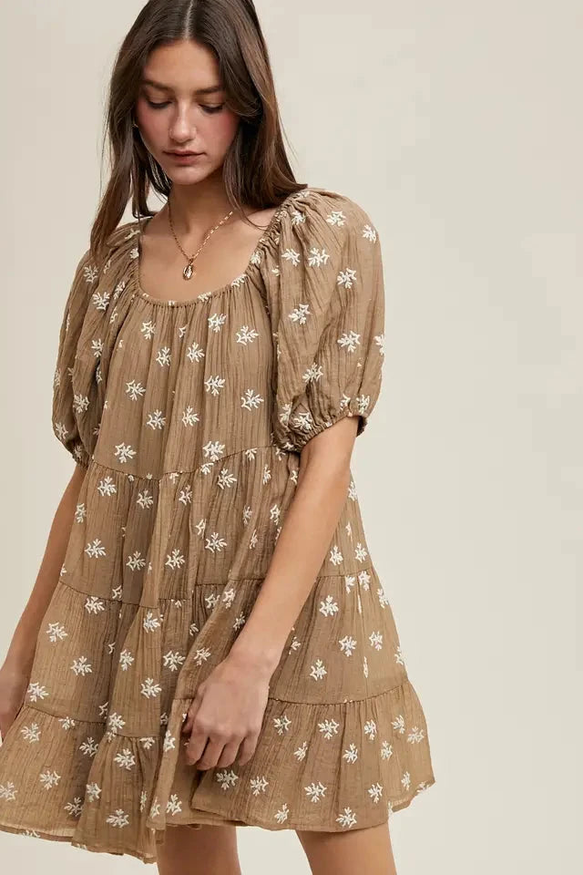 Woman wearing a brown floral dress against a neutral background