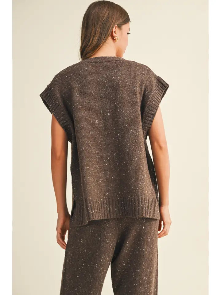 Woman wearing a brown knitted sleeveless top and pants on a beige background