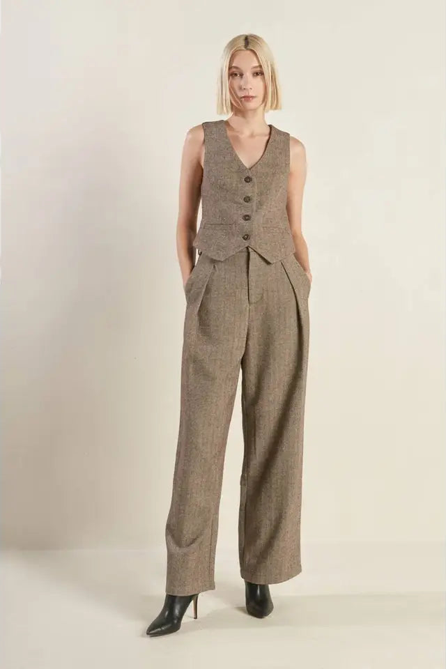 Woman wearing a brown checkered suit with a vest on a plain background