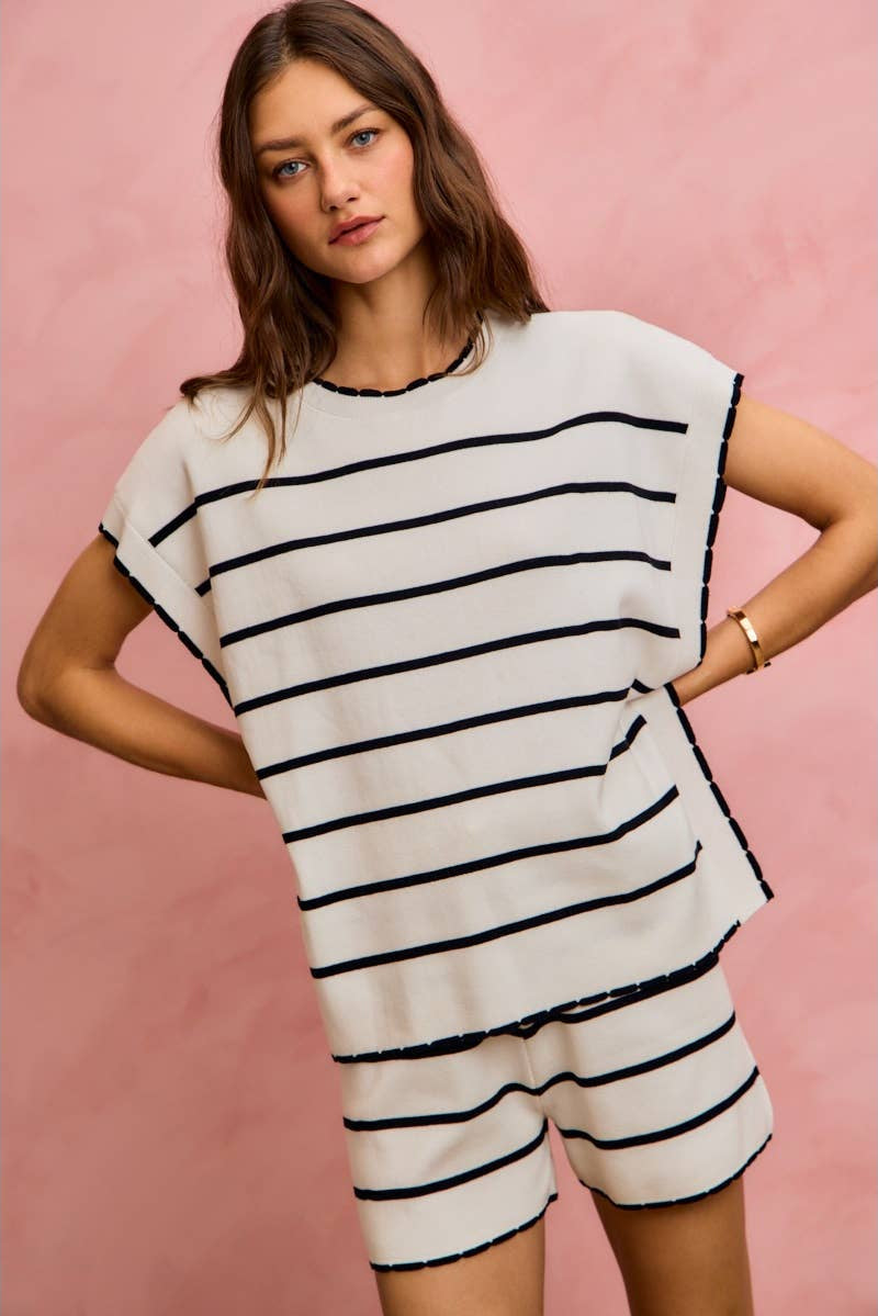 Woman wearing a black and white striped outfit against a pink background