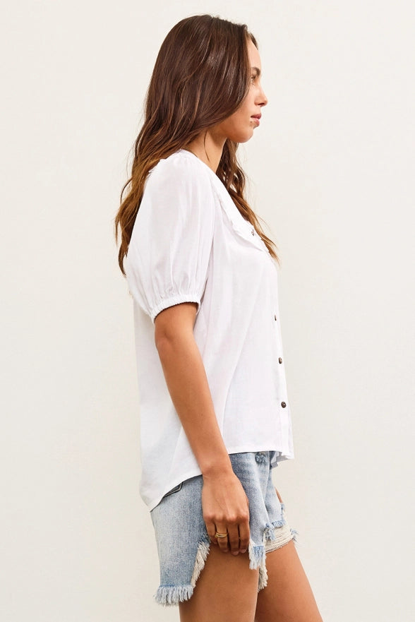 Woman wearing a white blouse and denim shorts against a plain background