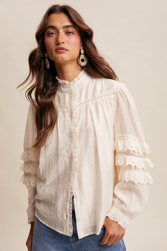 Woman wearing a white blouse with ruffled sleeves against a beige background