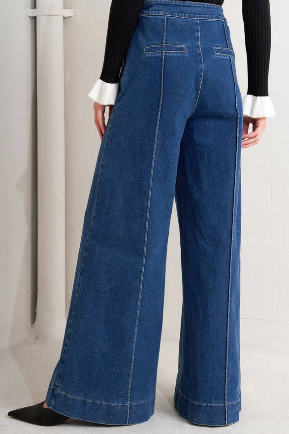 Wide-leg blue jeans worn by a person on a light gray background