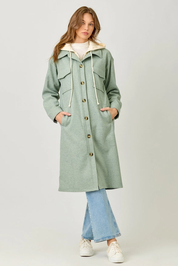 Woman wearing a light green coat with a white background