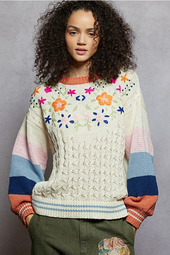 Woman wearing a colorful floral-patterned sweater against a gray background
