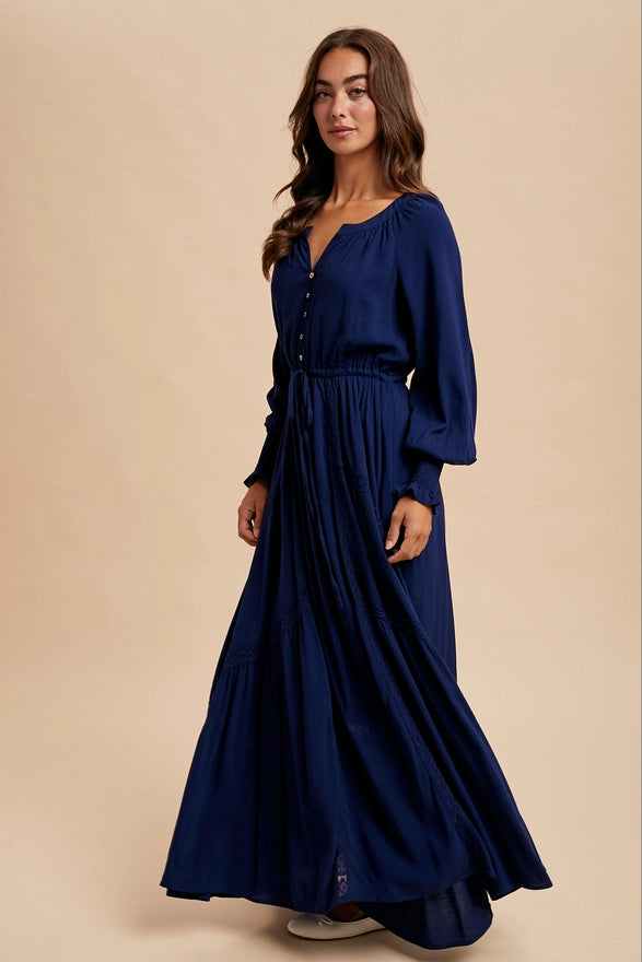 Woman wearing a navy color maxi dress with long sleeves on plain background
