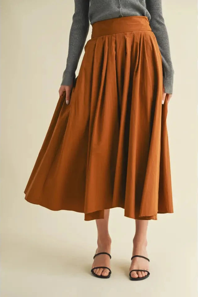 Person wearing a rust-colored skirt and gray top on a beige background