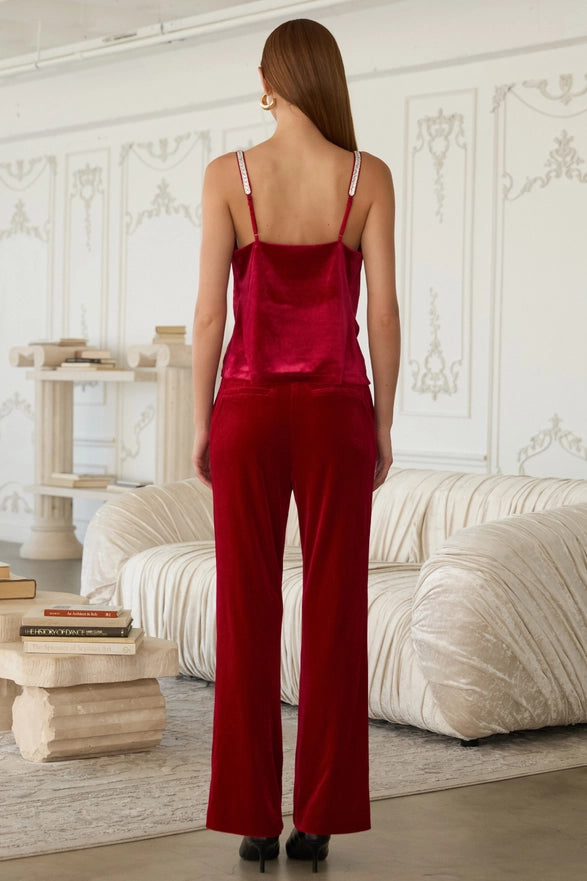 Woman wearing a red satin outfit in an elegant room with white walls and a beige sofa.