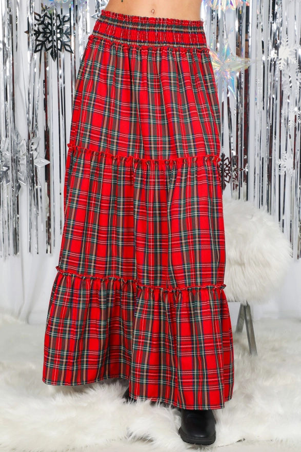 Red plaid skirt with ruffled layers on a white fur surface.