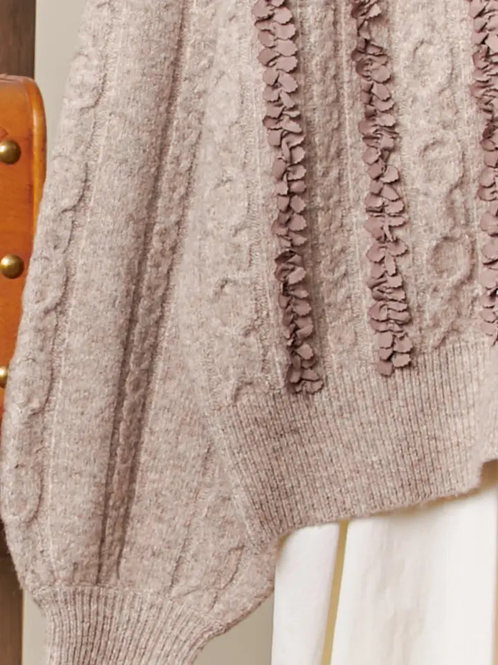 Close-up of a textured sweater with floral details on a neutral background
