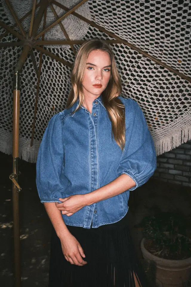 Woman wearing a blue denim shirt standing under a textured roof
