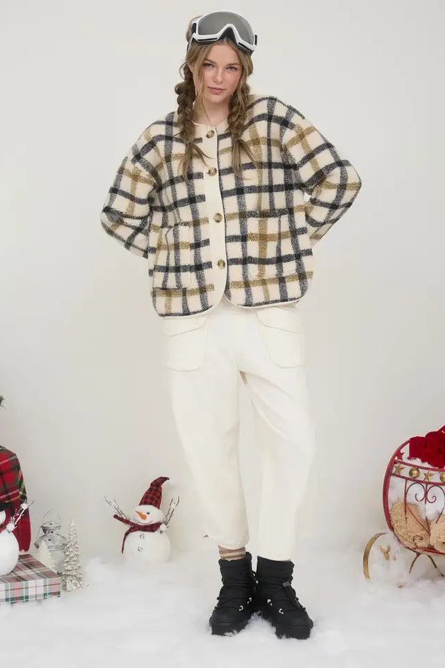 Person wearing a plaid jacket and white pants with festive decorations in the background.