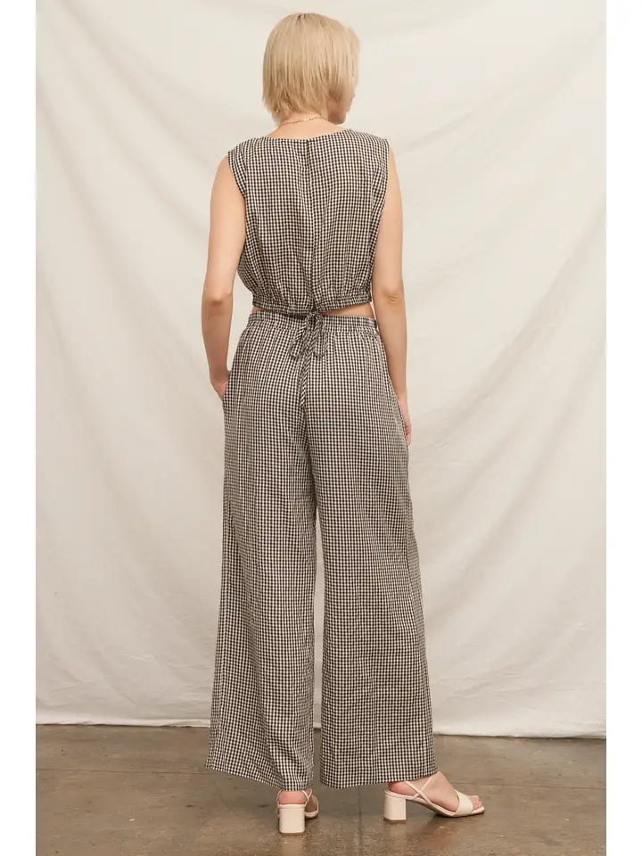 Woman wearing a checkered jumpsuit against a plain background