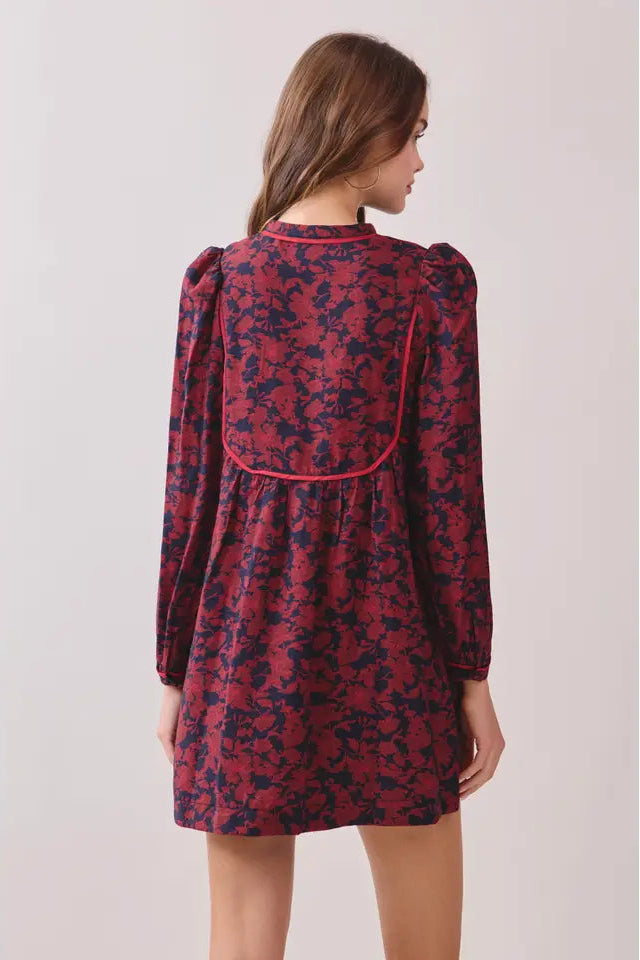 Woman wearing a red floral dress against a plain background