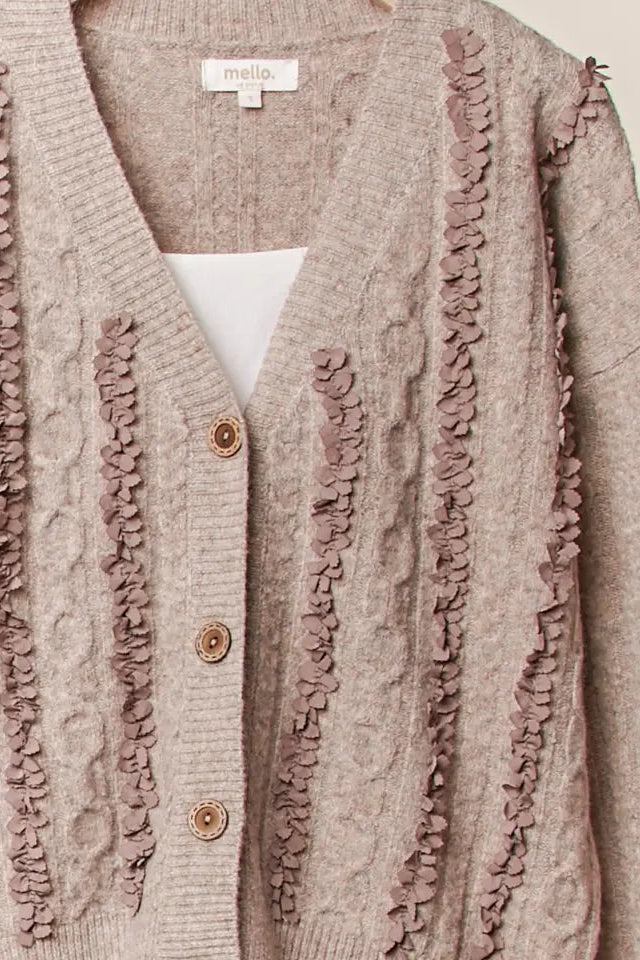Brown cardigan with ruffled details and a visible brand label on a light background