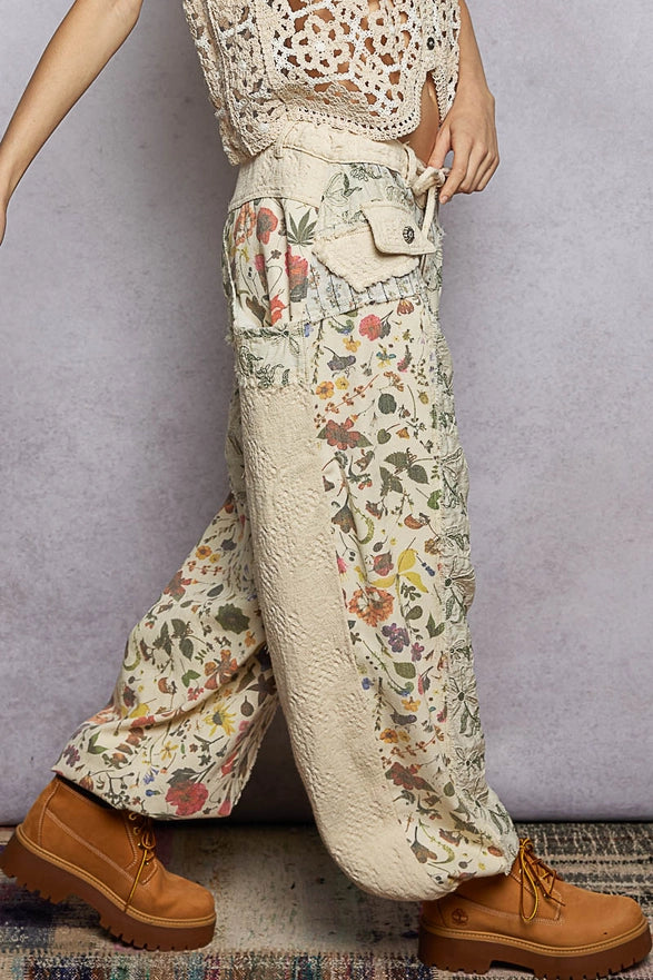 Person wearing floral-patterned pants with a textured top against a gray background