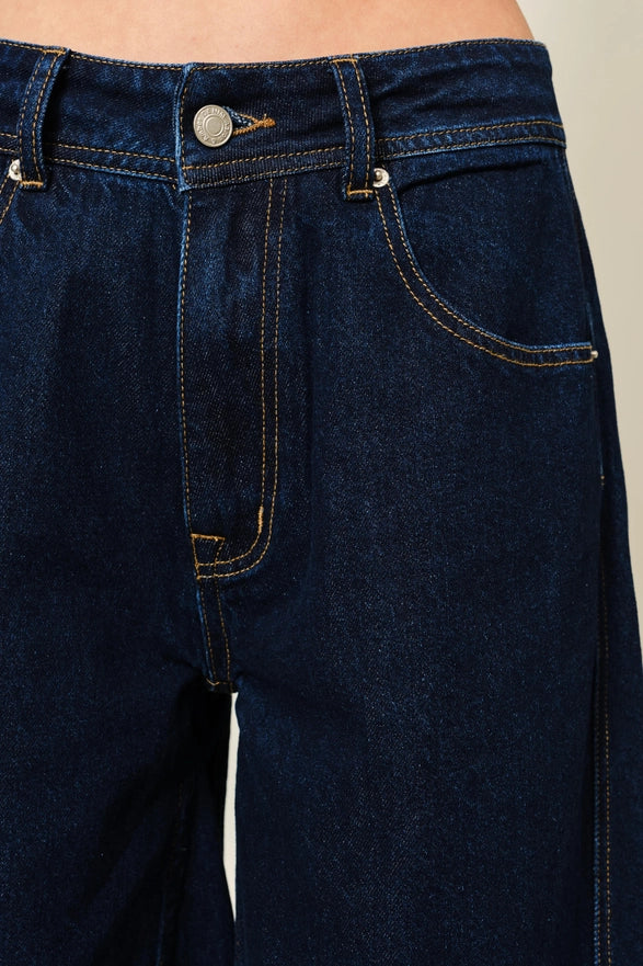Close-up of dark blue jeans with a beige background