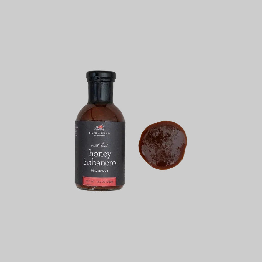 A bottle of Sweet Heat Honey Habanero BBQ sauce with a label showing the product name and a small circular image of the sauce applied to a piece of meat.