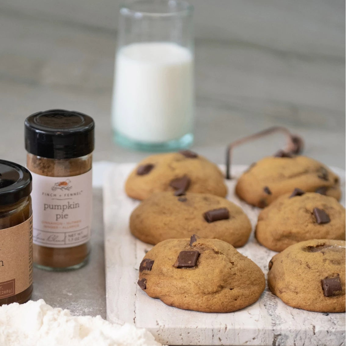 Cookies on a tray with pumpkin honey and pumpkin pie spice, surrounded by flour and eggs.