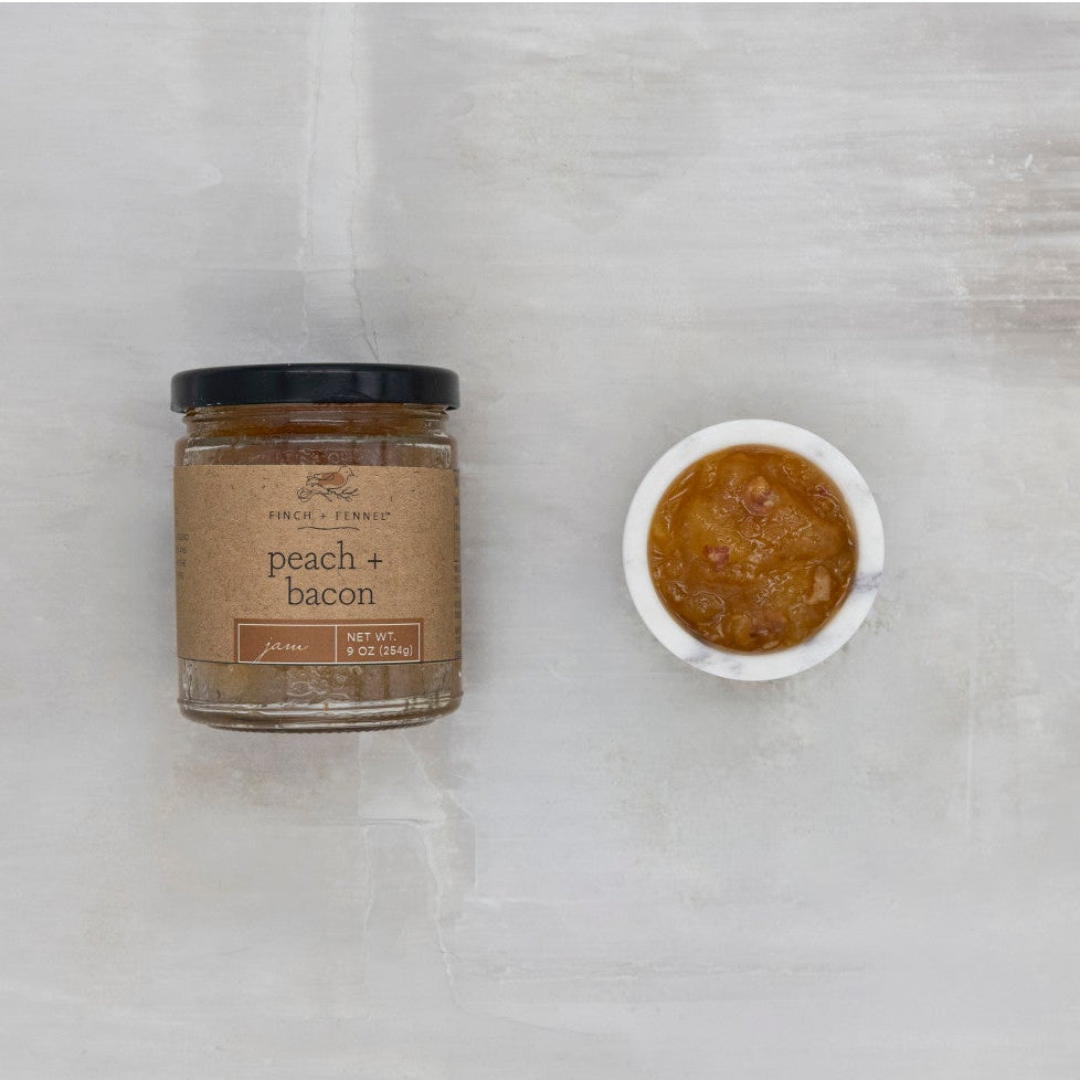 Jar of 'Peach + Bacon' spread next to a small bowl of the spread on a light gray background