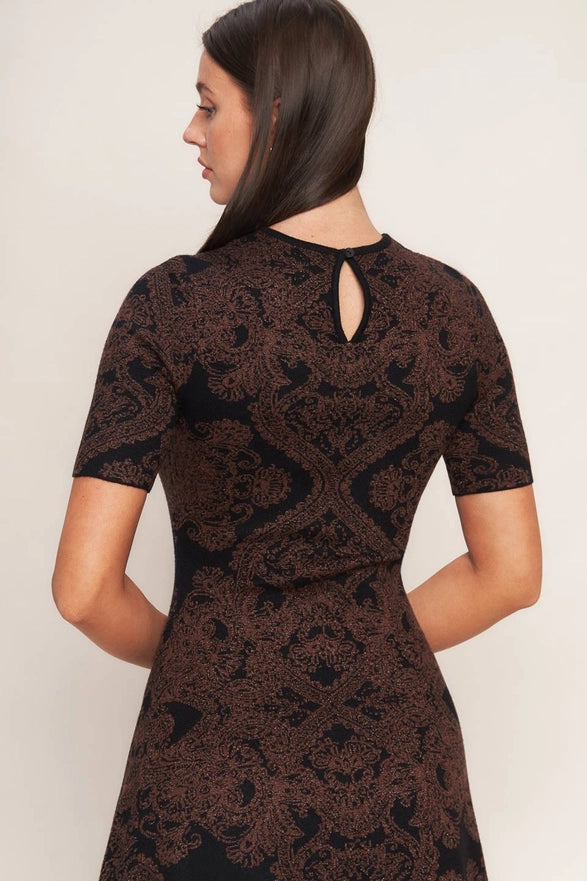 Woman wearing a black lace dress with a cutout back on a white background