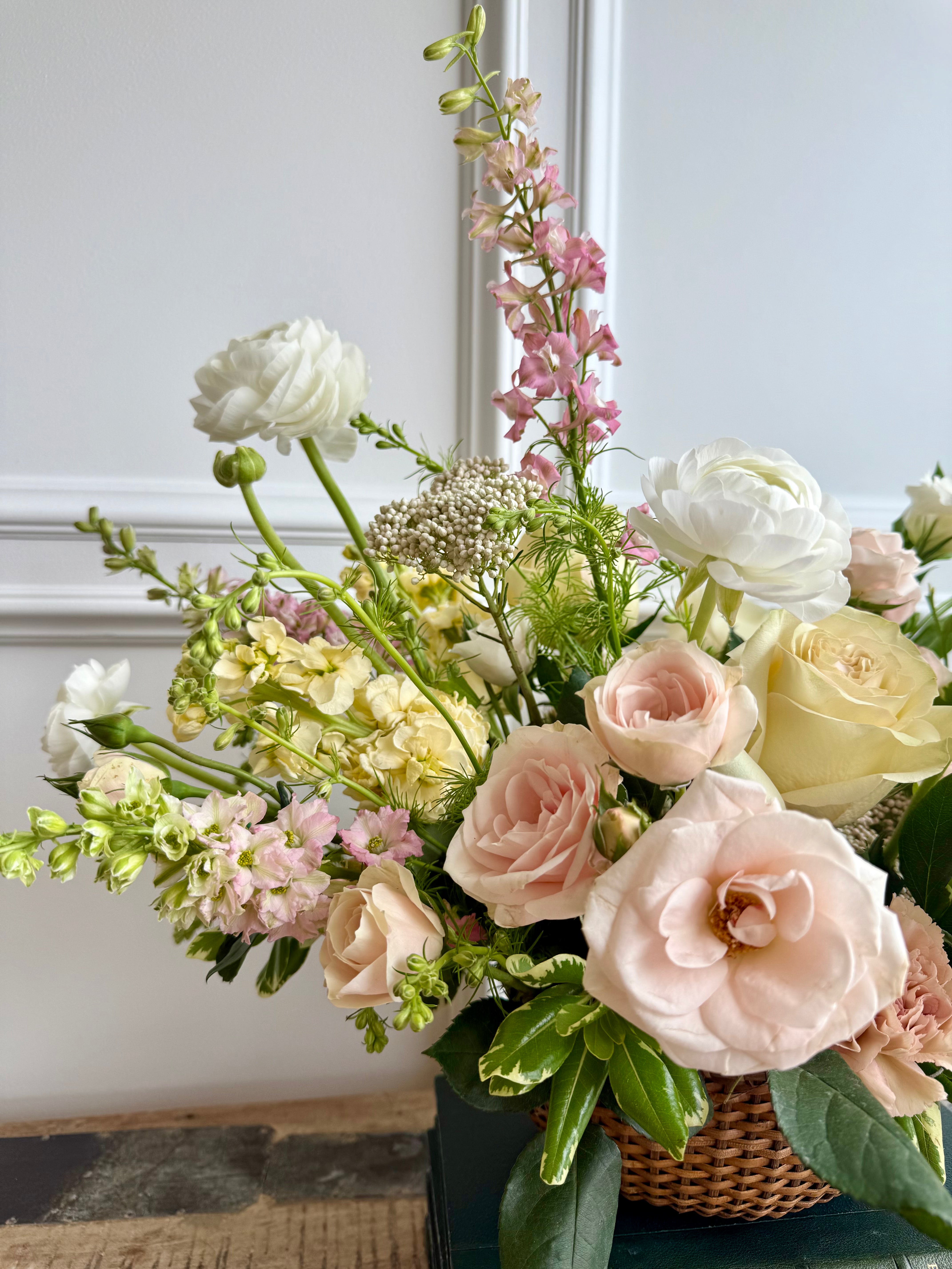 A soft and elegant floral arrangement in a woven basket.