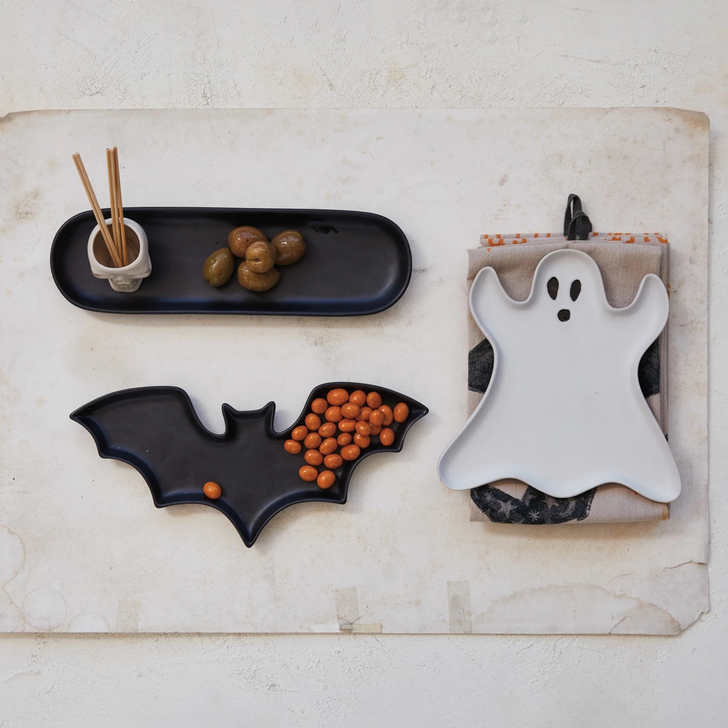 Halloween-themed snack trays with bat, ghost, and spider designs on a textured surface.