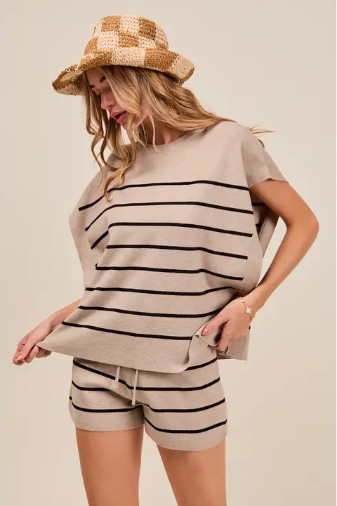 Woman wearing a striped outfit with a hat on a plain background