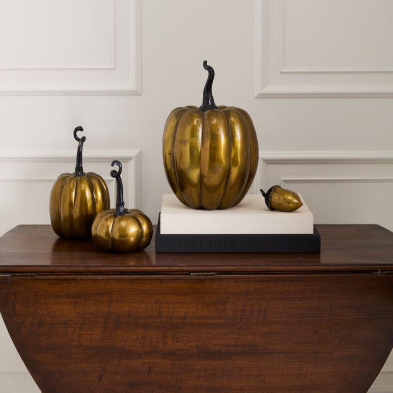 Decorative gold pumpkins on a wooden surface with a white paneled wall background