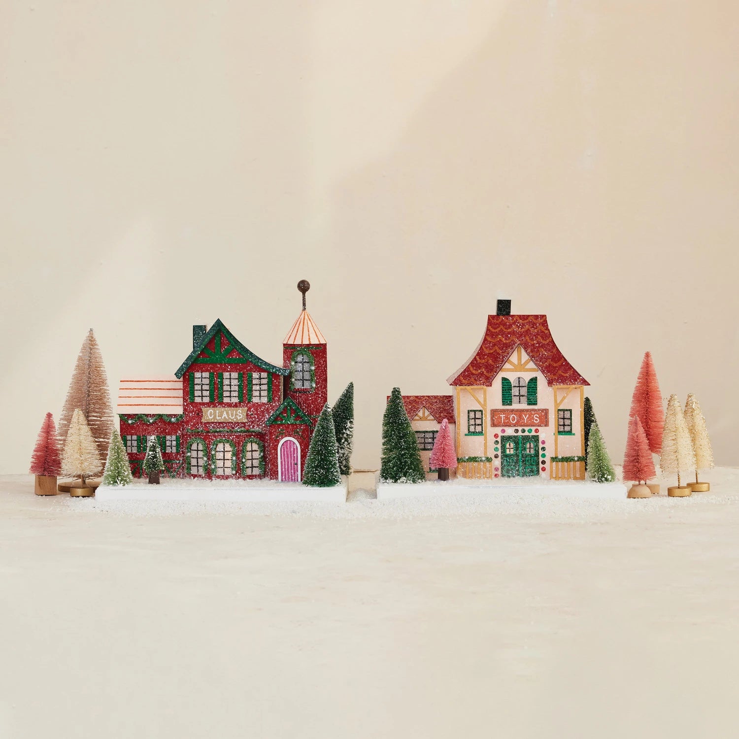 Small model of a snowy village with colorful houses and trees on a beige background